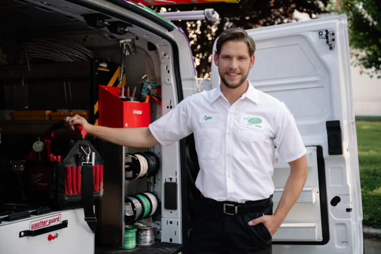 A Jerry Kelly technician in a white uniform stands by a neatly organized service van, ready with tools to assist customers.
